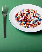 Close-up of tablets on plate with fork on green background