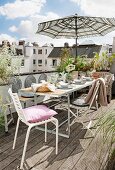 Gedeckter Tisch mit Stühlen und Sonnenschirm auf dem Balkon