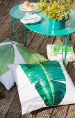 Floor cushions with leaf motifs and set of metal tables on balcony