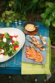 Mangosalat mit Mini-Mozzarella, Hähnchen-Saté, Garnelen-Spieße und Dip im Freien