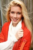 Portrait of beautiful blonde woman with long hair in white and orange cardigan, smiling