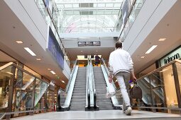 ein Mann betritt die Rolltreppe in einem Kaufhaus