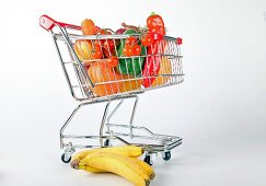 Shopping cart with vegetables and fruits on white background