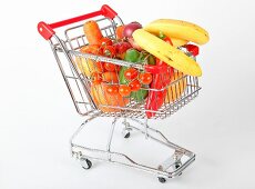 Shopping cart with vegetables and fruits on white background