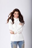 Portrait of pretty woman with dark hair in white turtleneck sweater and jeans, smiling