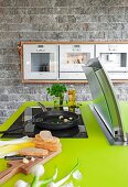 Green counter top in kitchen with pan on hob and cooker hood