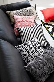 Black leather sofa with colourful patterned pillows
