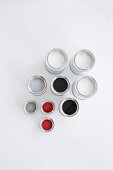 Red, grey, black and white paint in colour pots on white background