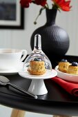 Muffins with blueberries, tea cup and black vase on black table