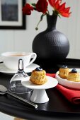 Muffins with blueberries, tea cup and black vase on black table