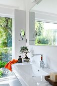 Luxurious bathroom with sink, large windows and orange accessories