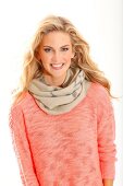 Portrait of pretty blonde woman wearing apricot colour sweater and scarf, smiling