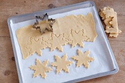 Snowflake shapes being cut out of biscuit dough