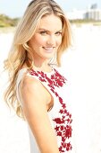 Blonde woman with long hair in a summer dress on the beach