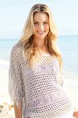 Blonde woman with long hair in a crochet shirt on the beach