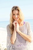 Blonde woman with long hair in a crochet shirt on the beach