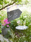 A placard hanging in a garden showing the way to a party