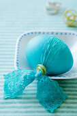 A turquoise Easter egg with a lace bow