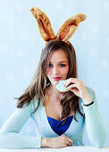 A woman wearing bunny ears eating a biscuit