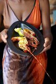 A woman serving grilled crayfish with garam masala