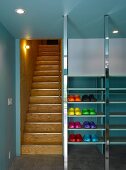 Lobby with colorful plastic shoes in metal shelves next to a wooden staircase