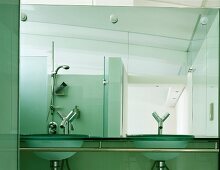 Designer bath with glass wash basins and designer fittings in front of a mirrored wall