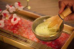 Mixing Japanese Matcha Green Tea in a Ceremonial Bowl with Whisk