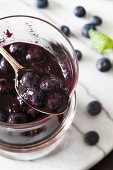 Homemade Blueberry Compote in a Spoon Above a Jar