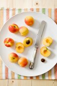 A plate of fresh apricots and a knife, whole and halved