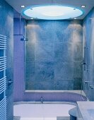 Modernes Bad mit grauen Fliesen an Wand und kreisförmigem Deckenlicht über Badewanne