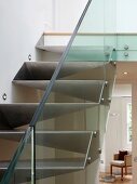 Detail of made-to-measure metal staircase with glass balustrade and view through open living room door