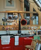 Vintage Küchenzeile mit rot lackierter Front und hängenden Pfannen und Töpfen