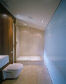 Minimalist bathroom with sand-colored floor and wall tiles and glass shower enclosure