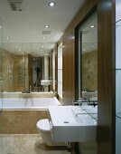 Moderner Waschtisch mit raumhohem Holzrahmen und Badewanne vor verspiegelter Wand