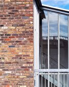 Brick facade of a home with stairway enclosed in glass