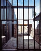 Steel and glass facade with open patio door and view of a courtyard