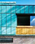 Turquoise colored panels on the wall of a house above a brick facade