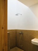 Minimalistischer Duschbereich mit halbhoher Steinverkleidung