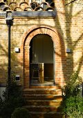 House facade with brick round arch and view through an open door into the kitchen