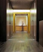 Modern minimalist lobby with built-in wooden closets and integrated strip lighting and view of a man in front of a sideboard