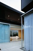 Courtyard of a contemporary home with partially closed curtains at the window and view of the living room