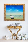 Goldgerahmtes Bild über einem Wandtisch im Rokoko-Stil und Porzellangeschirr