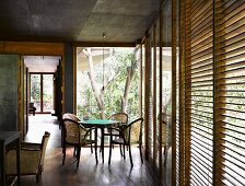 Traditional-style dining area in front of open terrace door and closed wooden blinds on windows