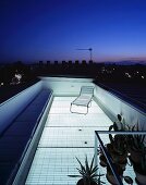 Durch transparenten Boden beleuchtete Dachterrasse unter städtischem Abendhimmel