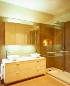 Reflections on glass wall of shower and mirrored cupboard in modern bathroom with two round sit-on basins