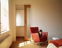 Katze auf Designer-Ledersessel in naturfarbenem Schlafzimmer mit Schiebetür zu Bad ensuite