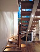 Open-structure, wooden spiral staircase with central steel support in front of window at twilight