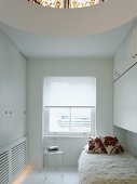 Weisses Gästezimmer mit kreisförmigen Deckenausschnitt über Bett mit Flokatidecke und schlichten Einbauschränken