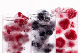 Three glasses of water with various berry ice cubes