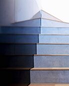 Concrete stairs with wooden treads next to black stone-tiled wall